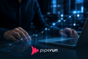 Imagem em ambiente corporativo escuro com iluminação em tons de azul, mostrando um profissional interagindo com um notebook enquanto um gráfico digital ascendente representa estratégias de revenue management e crescimento financeiro.