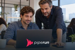 Vendedor usa um CRM simples no notebook enquanto o gestor comercial acompanha ao lado, em um escritório iluminado